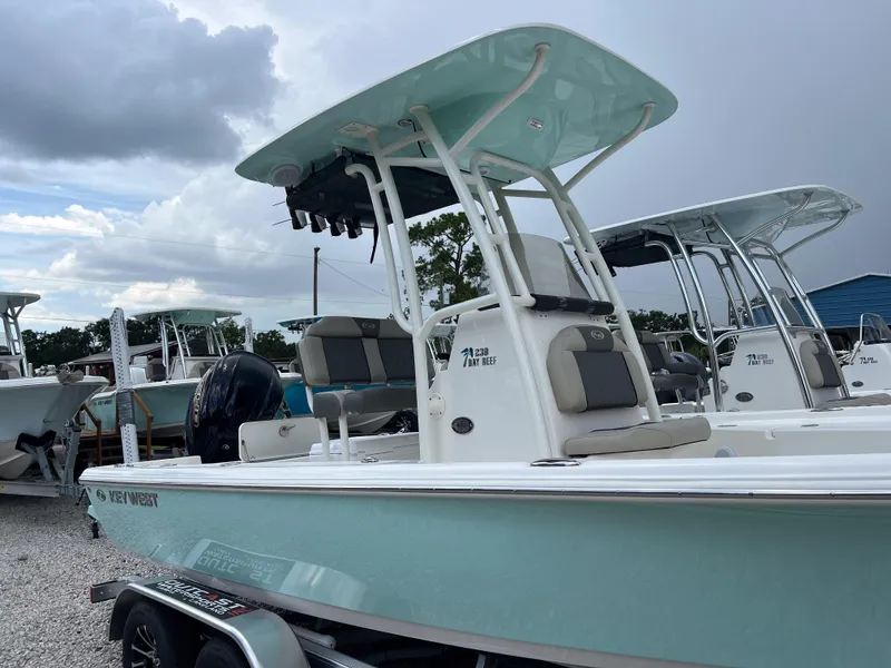 Slide: The Image of 2026 Key West 230 Bay Reef boat with T-top, parked on a trailer under cloudy skies. - 4