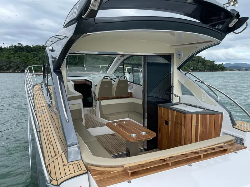 Slide: The Image of 2022 Evolve 400HT yacht interior with seating, table, and kitchenette on the water. - 2