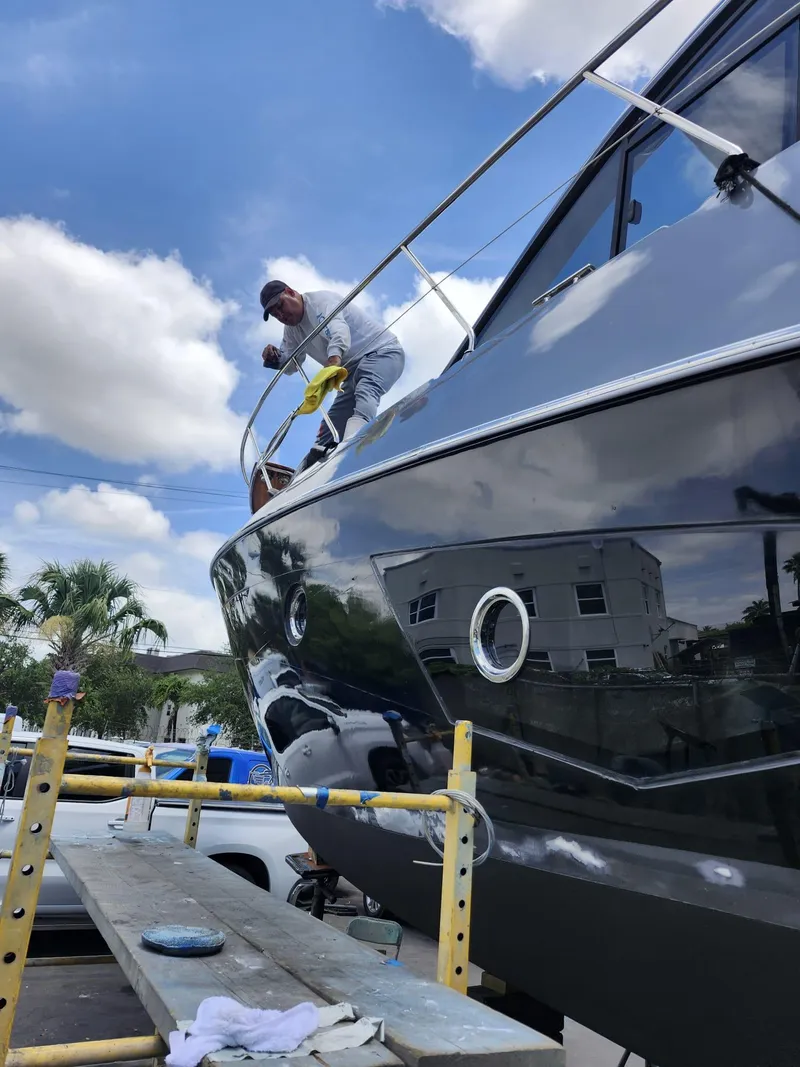 Slide: The Image of Man polishing a 2022 Evolve 400HT yacht on scaffolding under a blue sky. - 20