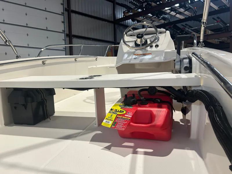 Slide: The Image of 2026 Boston Whaler 130 Super Sport interior with steering console and storage compartments. - 16