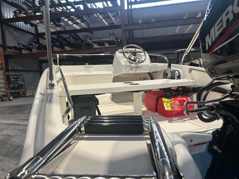 Slide: The Image of 2026 Boston Whaler 130 Super Sport boat interior with steering wheel and engine view. - 18