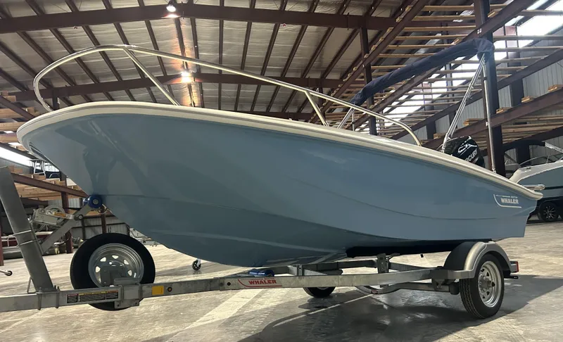 Slide: The Image of 2026 Boston Whaler 130 Super Sport boat on trailer in warehouse setting. - 4
