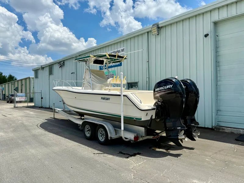 Slide: The Image of 1997 Pursuit 2470 Center Console boat on trailer, parked outside a warehouse. - 3
