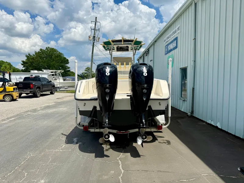 Slide: The Image of 1997 Pursuit 2470 Center Console boat with dual outboard motors, parked near a Yamaha building. - 4