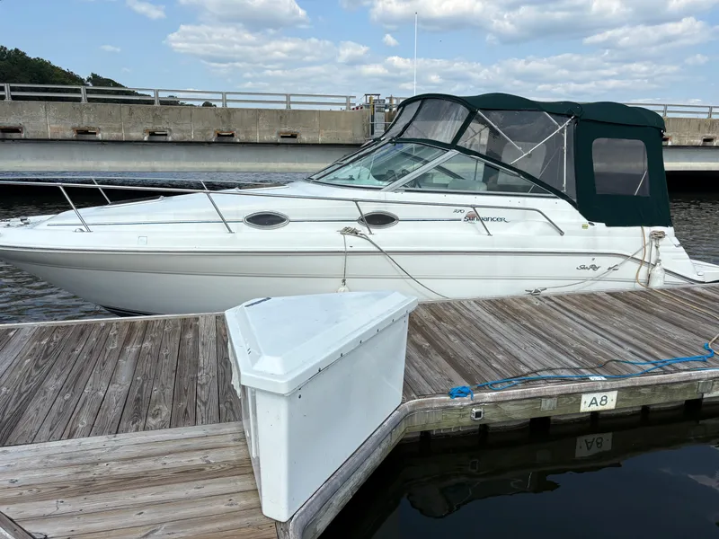 The Image of 1996 Sea Ray 270 Sundancer boat docked at a marina under a partly cloudy sky. - 1