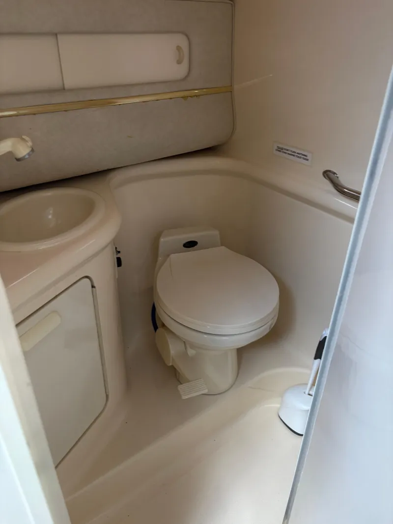 Slide: The Image of Compact bathroom in 1996 Sea Ray 270 Sundancer boat, featuring toilet and sink. - 12