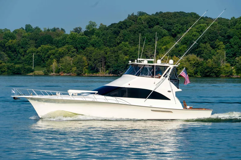 Slide: The Image of 1997 Ocean Yachts 60 Sport Fish cruising on a serene lake with lush green backdrop. - 4