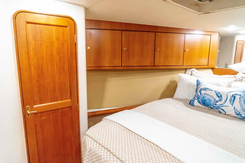 Slide: The Image of 1997 Ocean Yachts 60 Sport Fish cabin with wooden cabinets and cozy bedding. - 45
