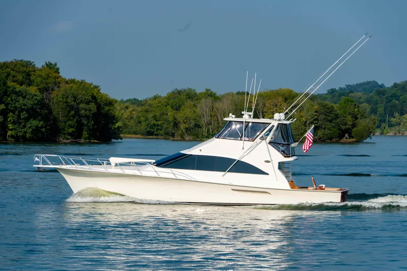 Slide: The Image of 1997 Ocean Yachts 60 Sport Fish cruising on a serene lake with lush green trees. - 5