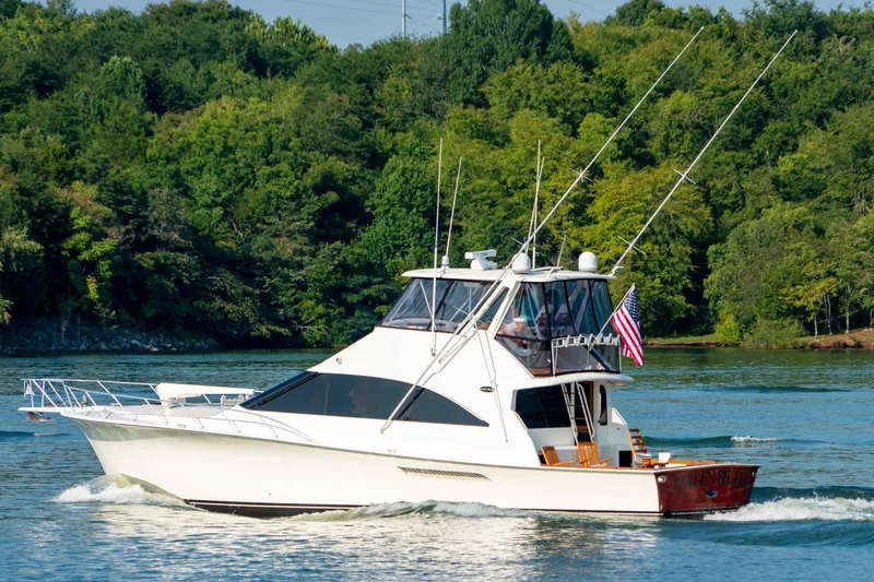 Slide: The Image of 1997 Ocean Yachts 60 Sport Fish cruising on a scenic river with lush greenery. - 6