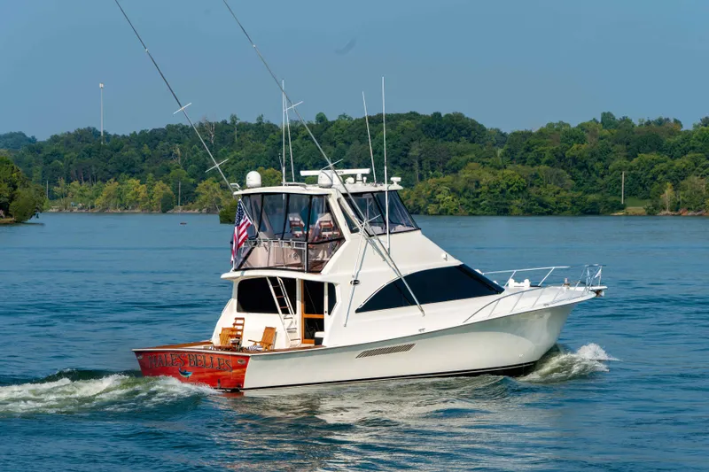 Slide: The Image of 1997 Ocean Yachts 60 Sport Fish cruising on a serene lake with lush green backdrop. - 8