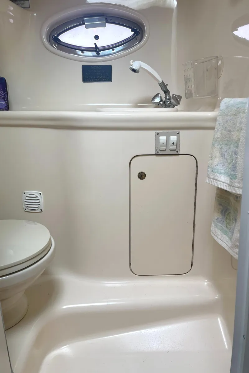 Slide: The Image of 2001 Sea Ray 290 Amberjack bathroom with toilet, sink, and porthole window. - 26
