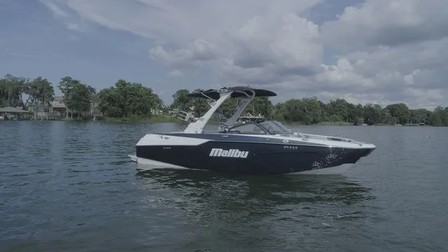 Slide: The Image of 2023 Malibu M220 boat on a serene lake. - 22