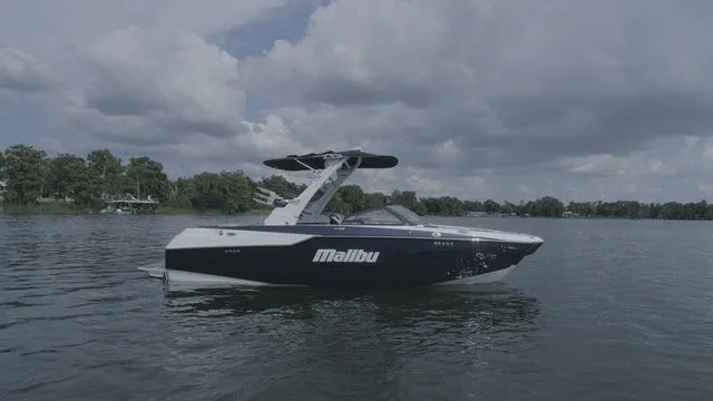 Slide: The Image of 2023 Malibu M220 boat on a calm lake. - 23