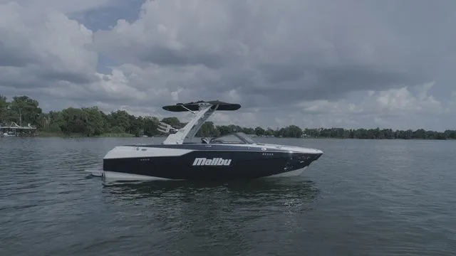 Slide: The Image of 2023 Malibu M220 boat on a calm lake. - 24