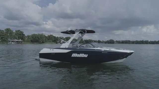 Slide: The Image of 2023 Malibu M220 boat on calm water under cloudy sky. - 26