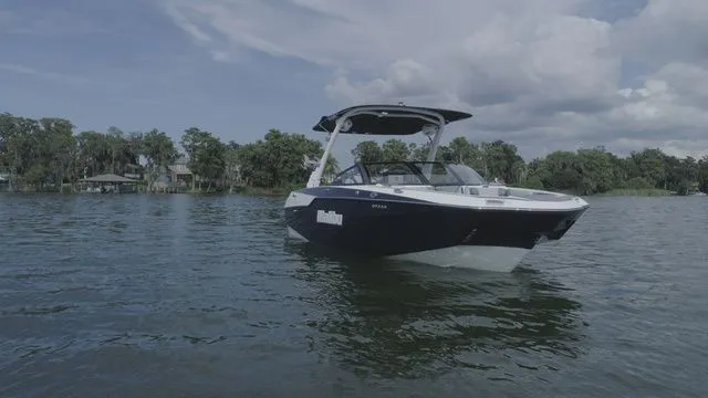 Slide: The Image of 2023 Malibu M220 boat on a serene lake. - 27