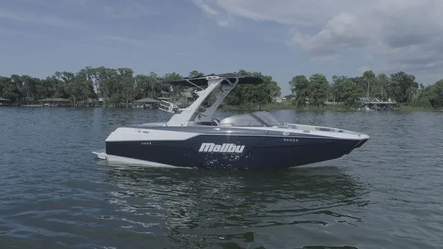 Slide: The Image of 2023 Malibu M220 boat on a serene lake. - 29