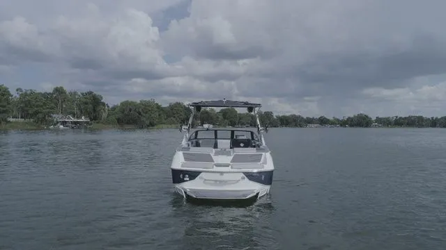 Slide: The Image of 2023 Malibu M220 boat on a calm lake under cloudy skies. - 31
