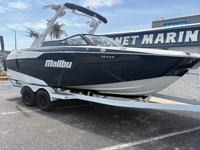 Slide: The Image of 2023 Malibu M220 boat on trailer outside marine store. - 32