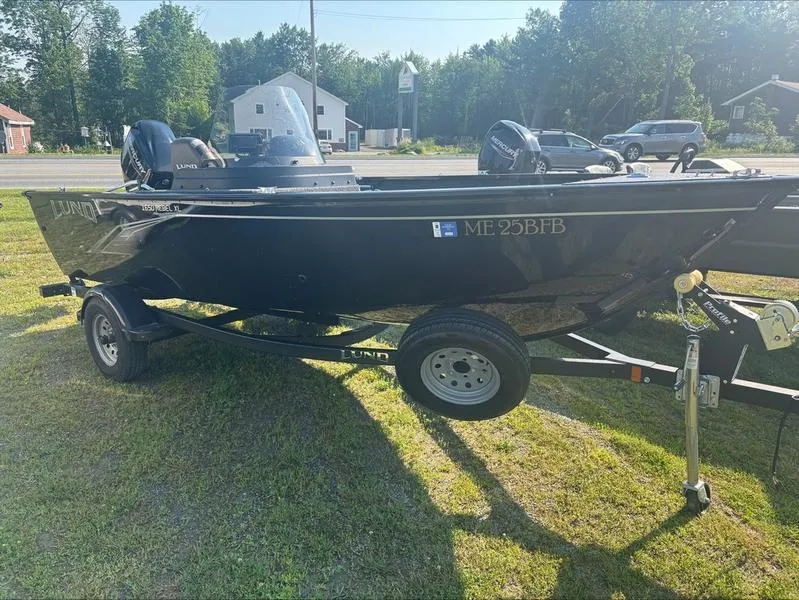Slide: The Image of 2022 Lund 1650 Rebel XL boat on trailer, parked on grass, with trees and road in background. - 3
