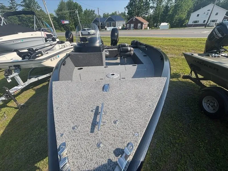 Slide: The Image of 2022 Lund 1650 Rebel XL fishing boat on display, parked on grass near other boats. - 8