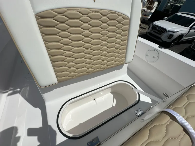 Slide: The Image of 2026 Twin Vee 22 Bay Cat boat interior with beige quilted seating and storage compartment. - 11