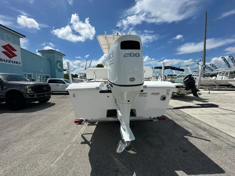 Slide: The Image of 2026 Twin Vee 22 Bay Cat boat with Suzuki outboard motor, parked outdoors. - 4