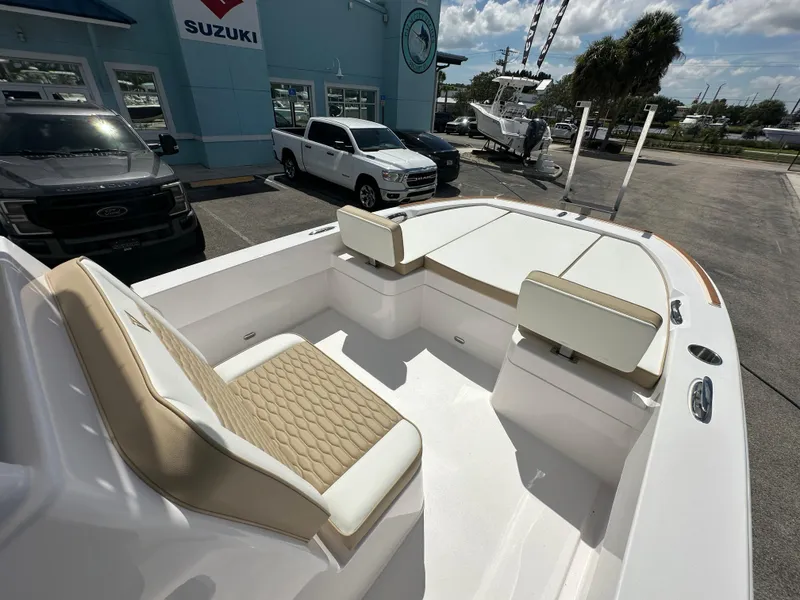 Slide: The Image of 2026 Twin Vee 22 Bay Cat boat interior with beige seating, parked at dealership. - 6
