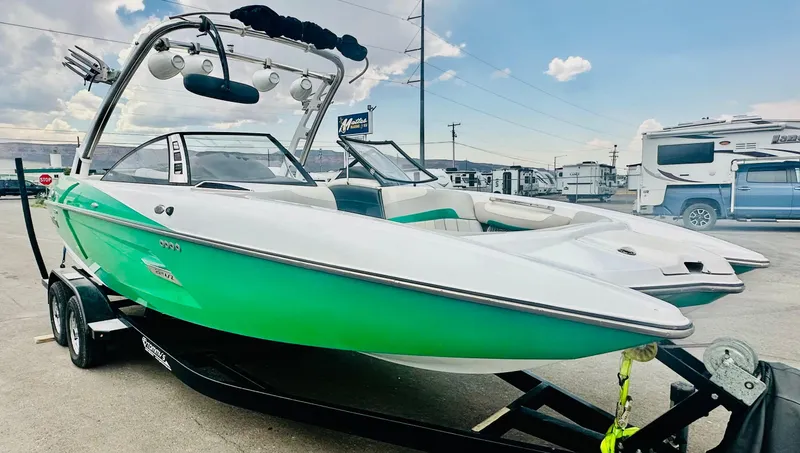 Slide: The Image of 2012 Malibu 22mxz boat with green and white design on a trailer. - 3