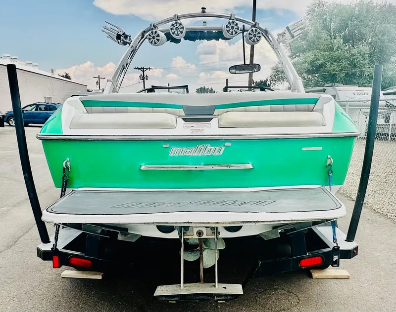 Slide: The Image of 2012 Malibu 22mxz boat, green exterior, rear view with wakeboard tower and speakers. - 5