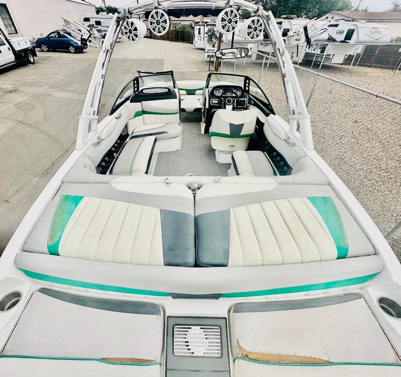 Slide: The Image of 2012 Malibu 22mxz boat interior with white and teal seating, speakers, and steering console. - 7