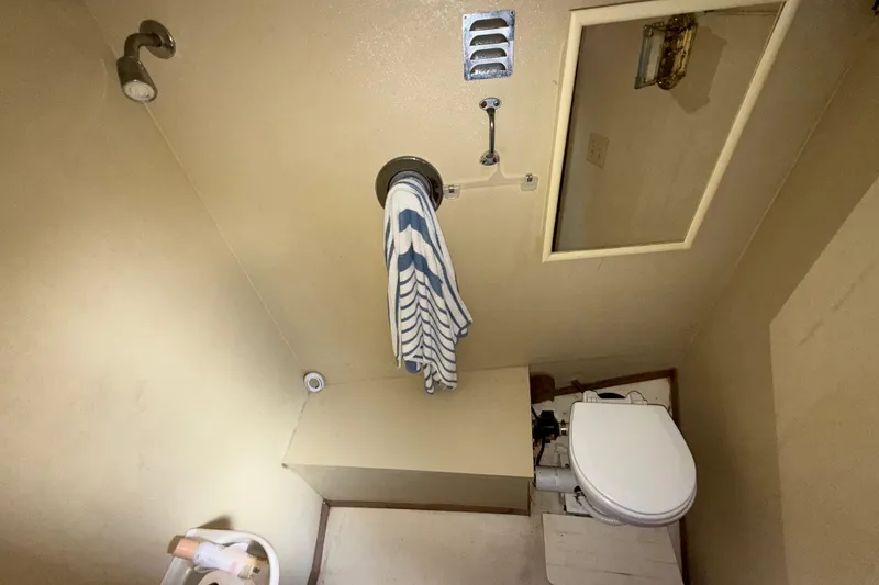 Slide: The Image of Compact bathroom with shower, toilet, and striped towel in a 1984 Custom 38 model. - 14