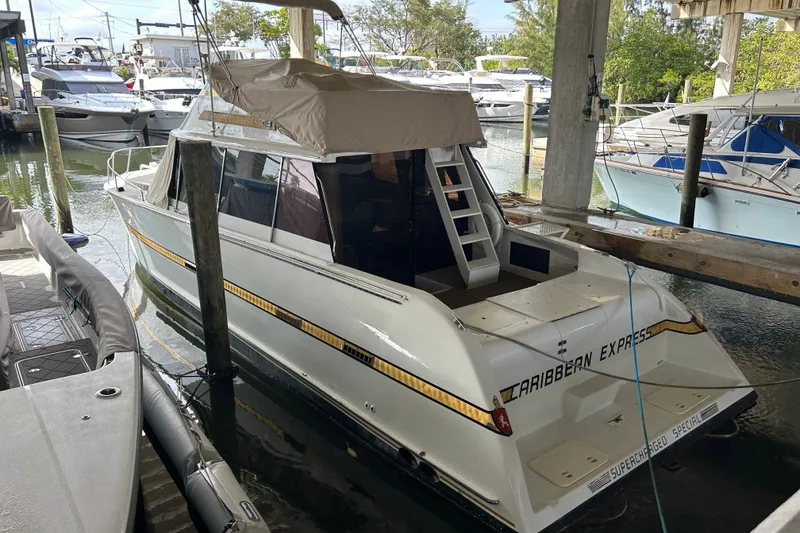 Slide: The Image of 1984 Custom 38 boat "Caribbean Express" docked in marina, covered deck, surrounded by other boats. - 21