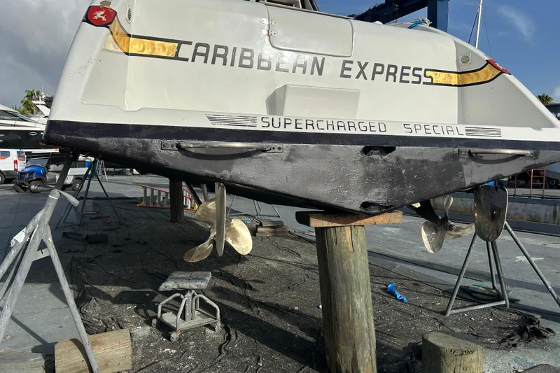 Slide: The Image of 1984 Custom 38 boat "Caribbean Express" on dry dock, showcasing propellers and hull. - 22
