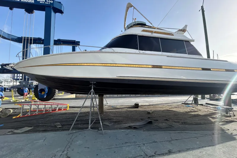 Slide: The Image of 1984 Custom 38 boat on dry dock, marina background, clear sky. - 24