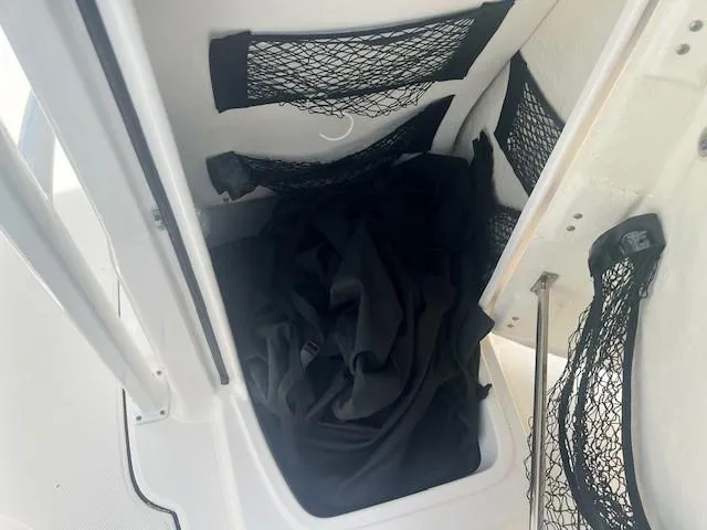 Slide: The Image of 2022 Robalo R222 Center Console storage compartment with netting and black fabric inside. - 21