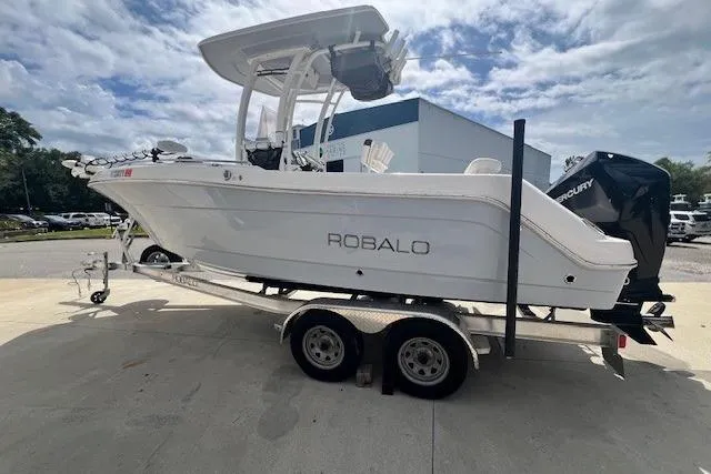 Slide: The Image of 2022 Robalo R222 Center Console boat on trailer, parked outdoors under cloudy sky. - 4