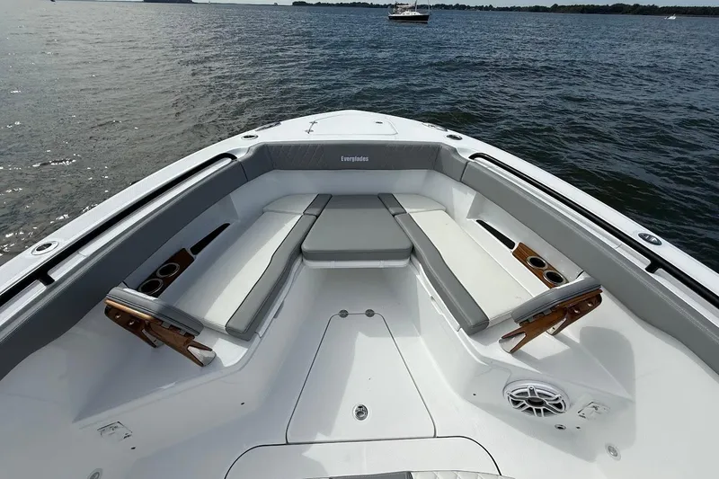 Slide: The Image of 2026 Everglades 375 Center Console boat interior with cushioned seating and cup holders on the water. - 33