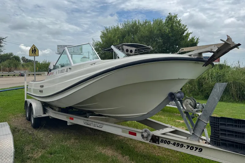 Slide: The Image of 1978 Boston Whaler 21 Outrage boat on trailer, parked on grass under cloudy sky. - 1