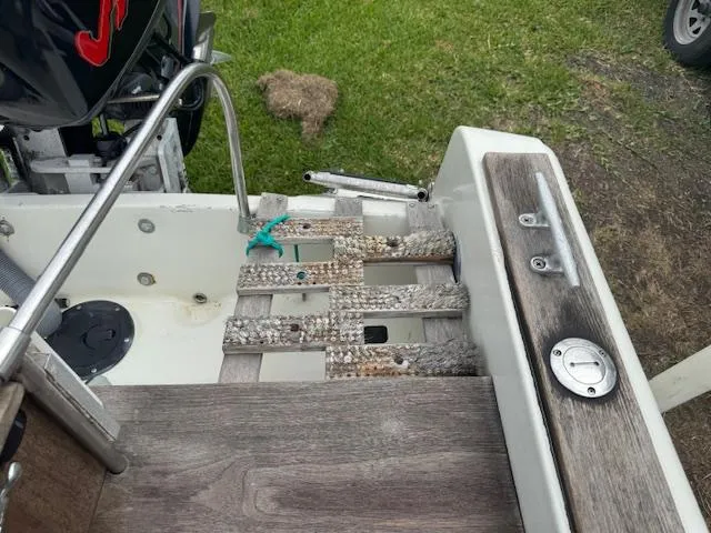 Slide: The Image of 1978 Boston Whaler 21 Outrage boat deck with ladder and motor, on grassy area. - 5