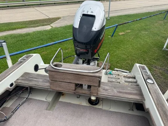 Slide: The Image of 1978 Boston Whaler 21 Outrage boat with outboard motor, wooden seating, and grassy background. - 6