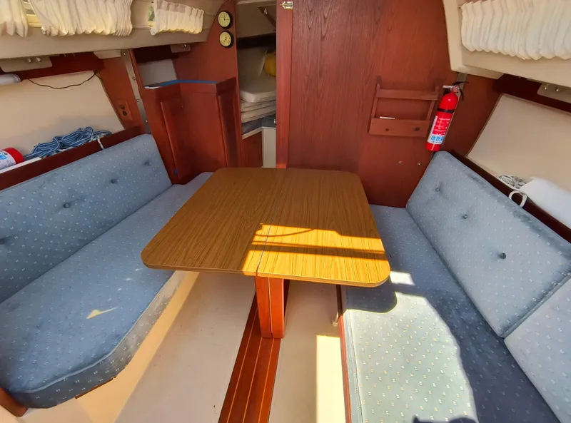 Slide: The Image of Interior of a 1985 Catalina 27 sailboat with blue seating and wooden table. - 17