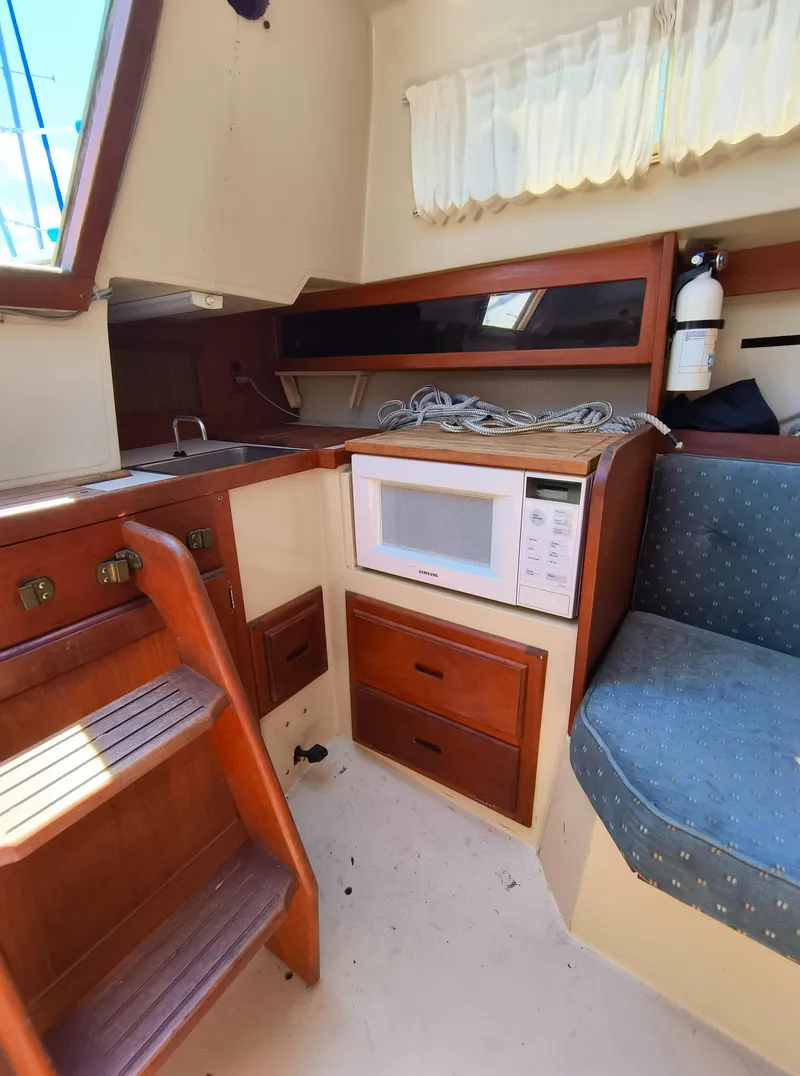 Slide: The Image of Interior of 1985 Catalina 27 sailboat with kitchen, microwave, and seating area. - 19