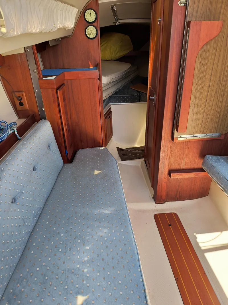 Slide: The Image of Interior of a 1985 Catalina 27 sailboat with blue seating and wooden cabinetry. - 20