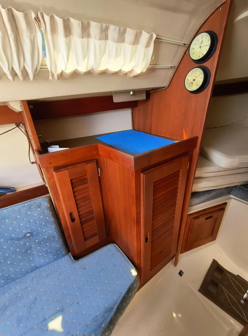 Slide: The Image of Interior of 1985 Catalina 27 sailboat with wooden cabinets and blue cushioned seating. - 21