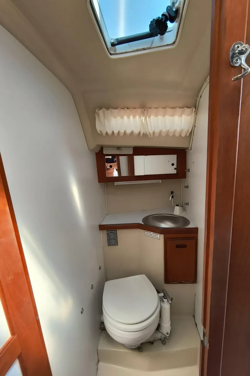 Slide: The Image of Compact bathroom in a 1985 Catalina 27 sailboat with toilet, sink, and skylight. - 23