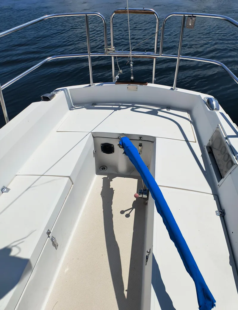 Slide: The Image of 1985 Catalina 27 sailboat deck with blue tiller cover, surrounded by calm water. - 8