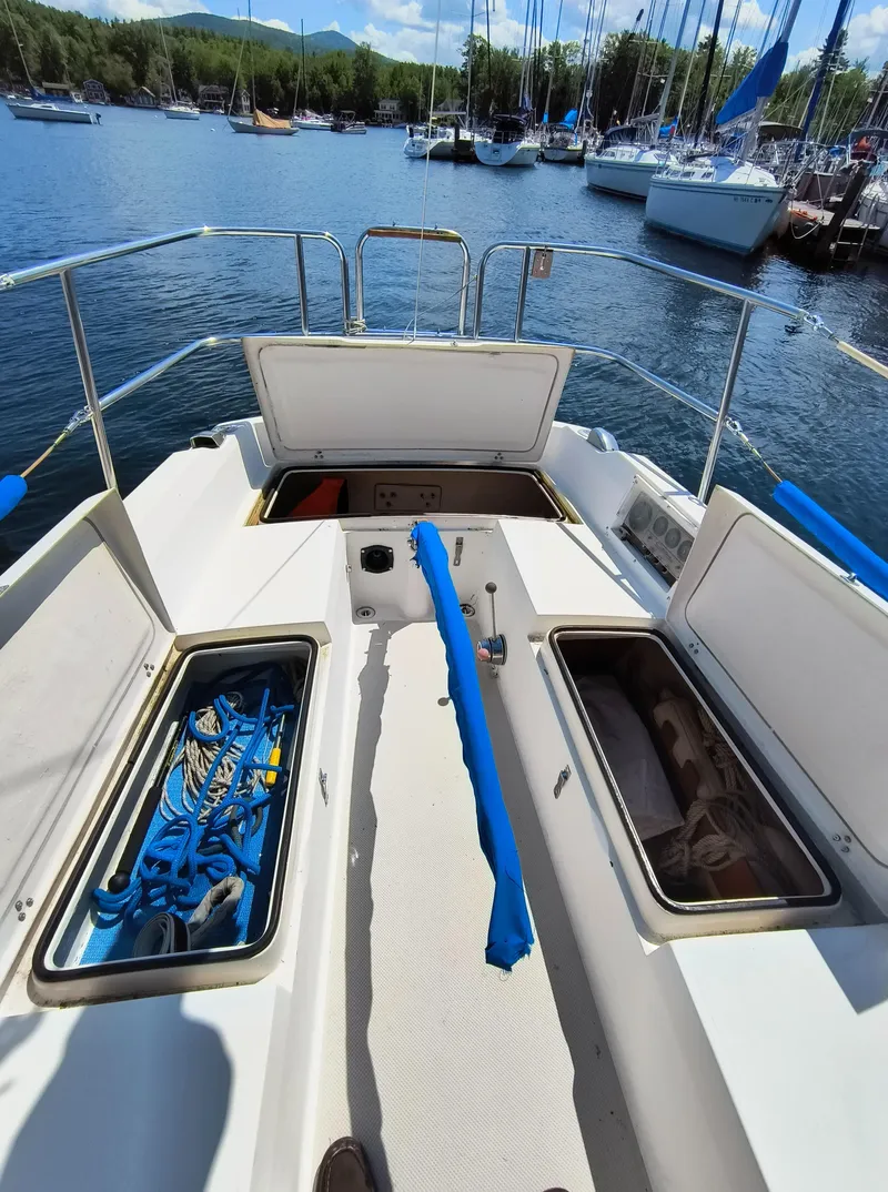 Slide: The Image of 1985 Catalina 27 sailboat cockpit with open storage compartments, docked in a marina. - 9