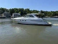 Slide: The Image of 2010 Regal 46 Sport Coupe yacht cruising on a serene lake with lush greenery. - 6